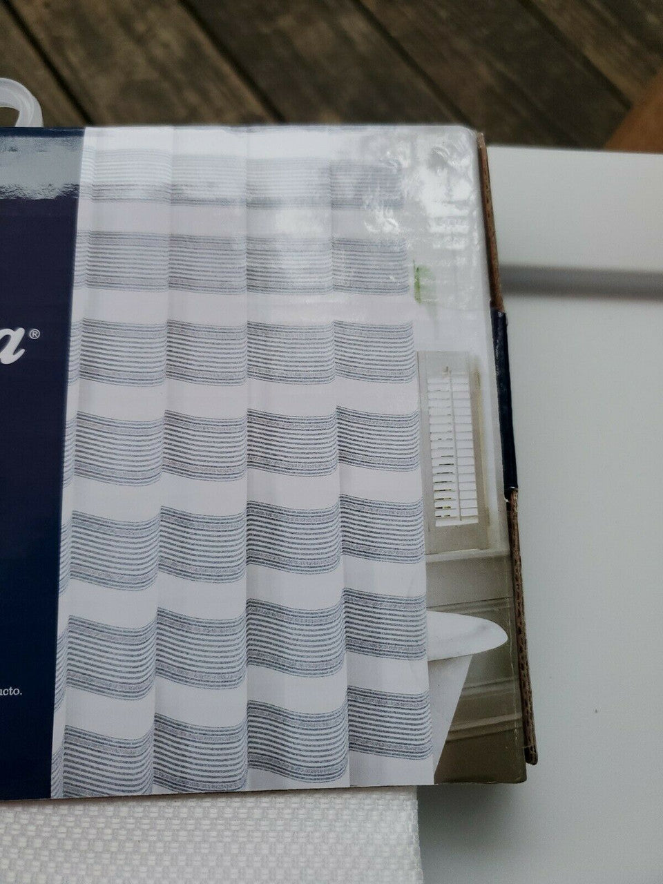 Textured blue and white striped shower curtain by Tommy Bahama folded with product label visible