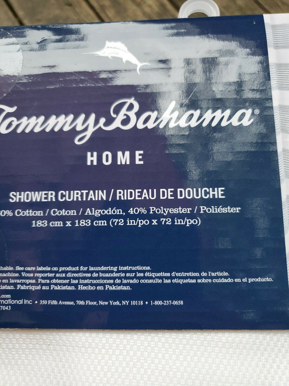 Textured blue and white striped shower curtain by Tommy Bahama folded with product label visible