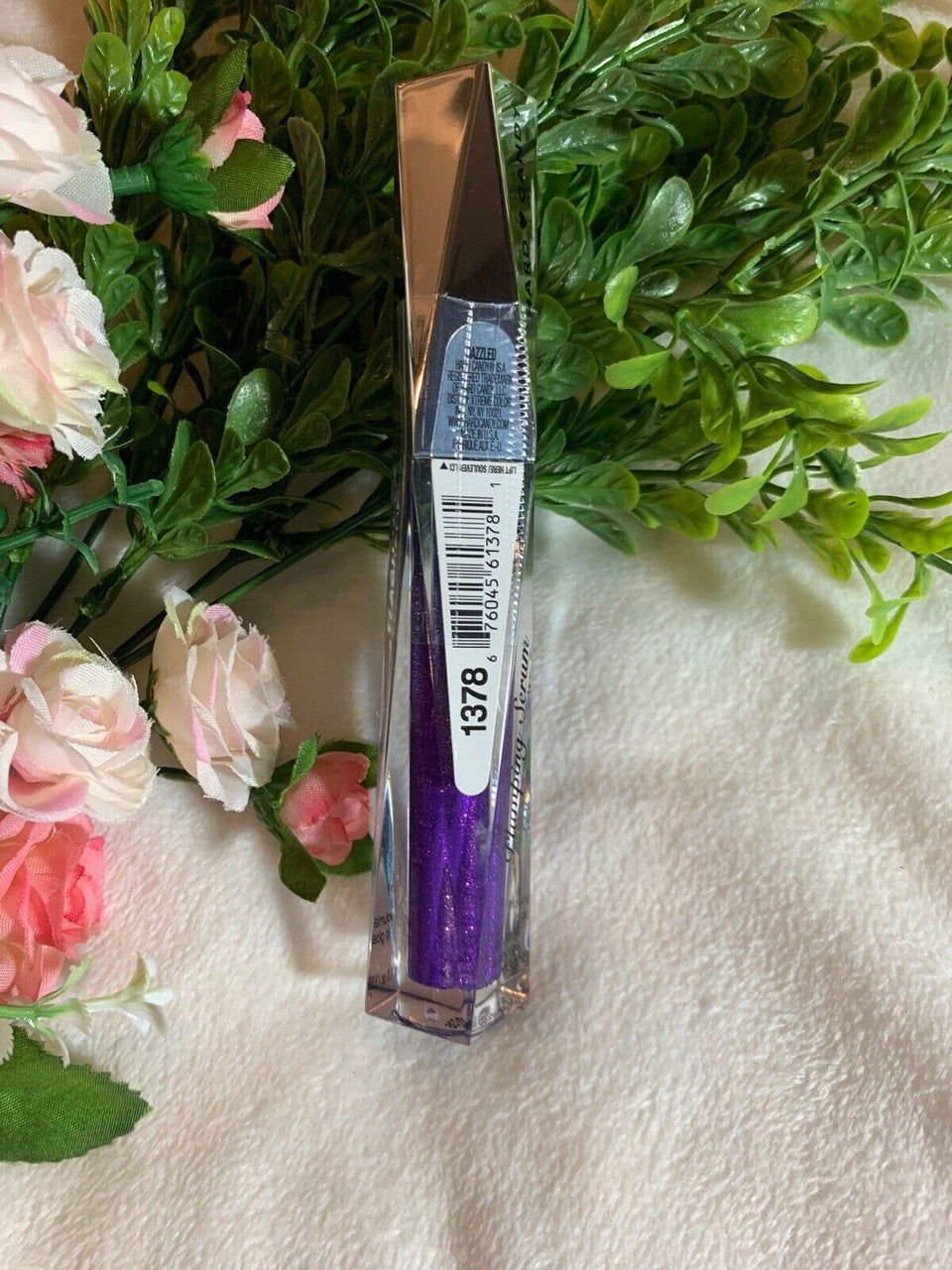 Hard Candy Dazzled #1378 lip plumping gloss in purple – sealed tube on floral background