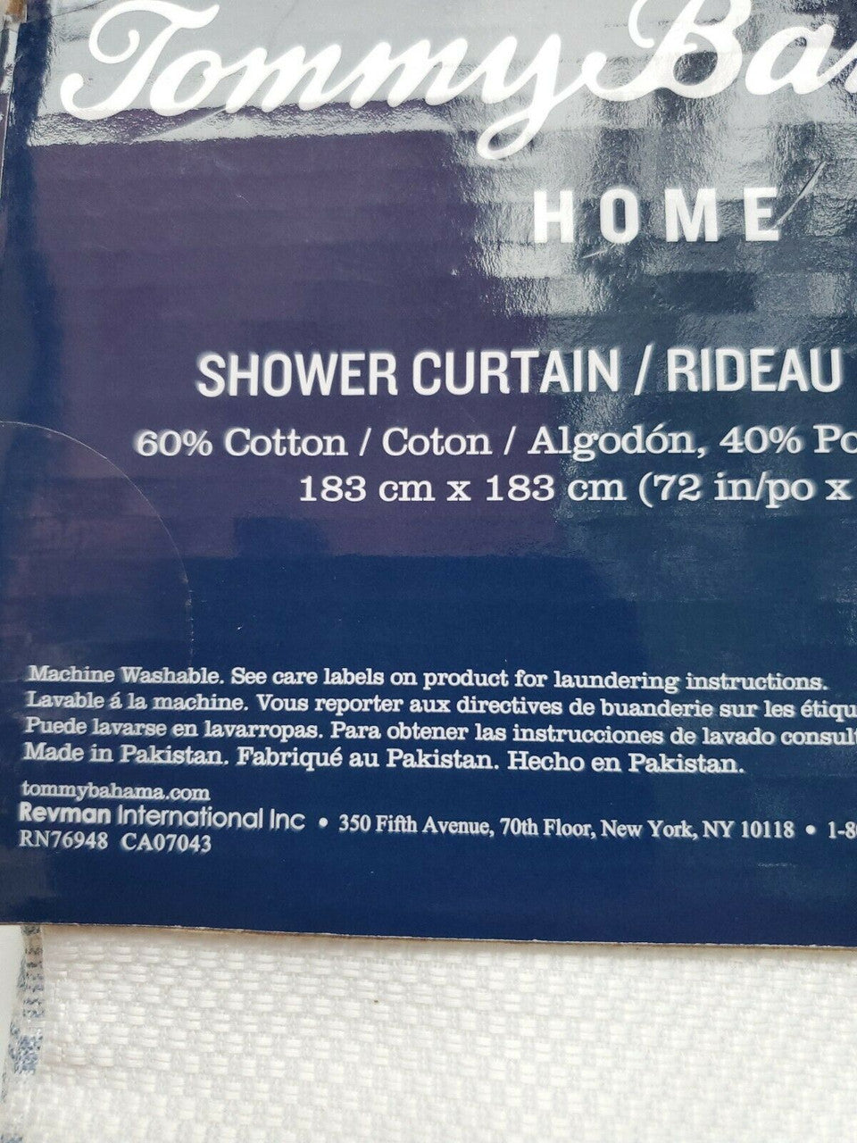 Textured blue and white striped shower curtain by Tommy Bahama folded with product label visible