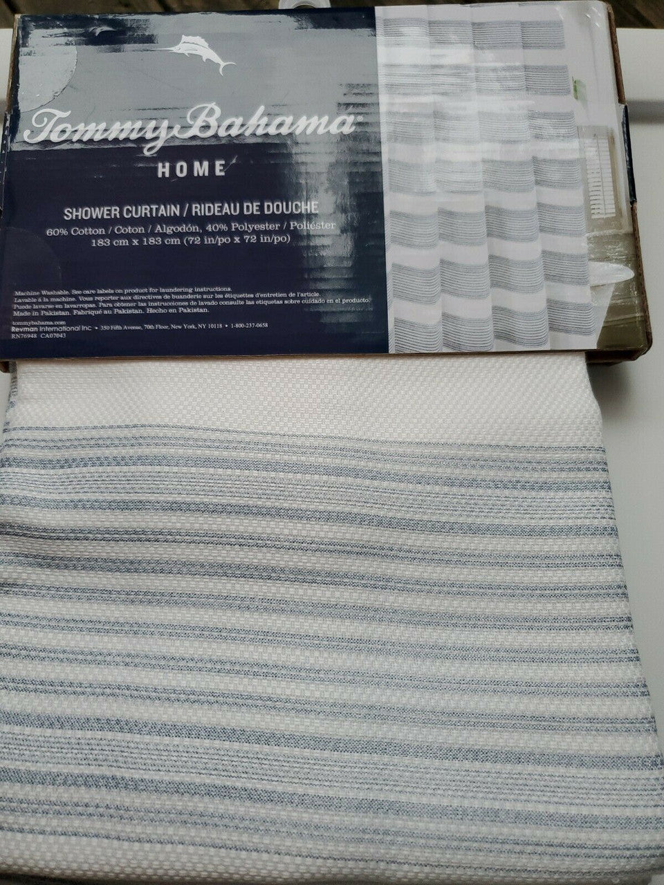 Textured blue and white striped shower curtain by Tommy Bahama folded with product label visible