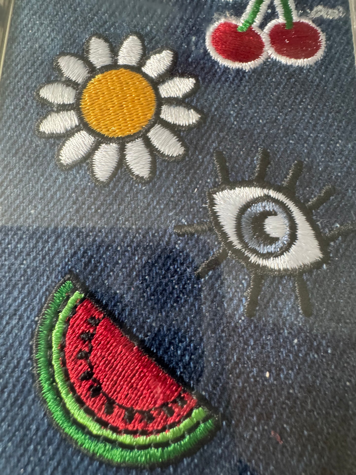 iPhone 7 denim phone case with embroidered watermelon, daisy, cherries, and eye design in original Luxe Double Up packaging.