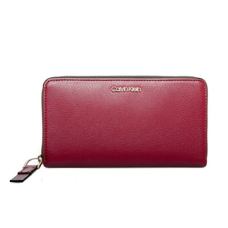 Calvin Klein Red Rock zip-around wristlet wallet with pebble-textured synthetic leather, metal logo on front, and organized interior with multiple card slots and compartments.