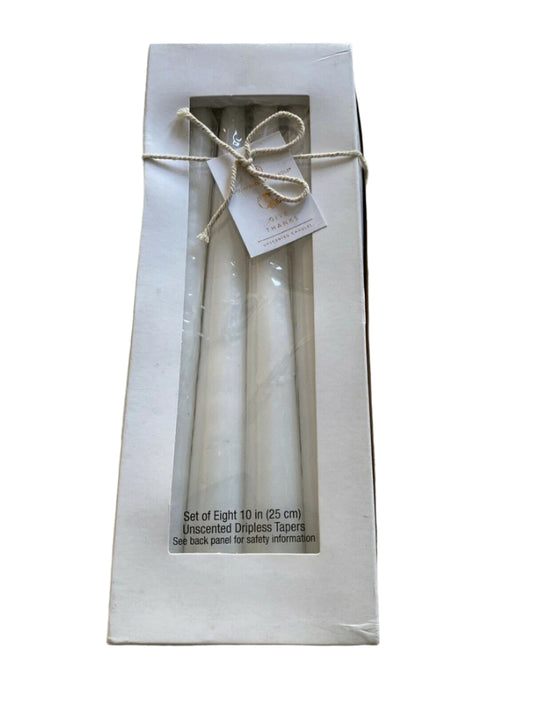 Set of 8 dripless unscented white taper candles in original packaging, ideal for elegant home decor or events