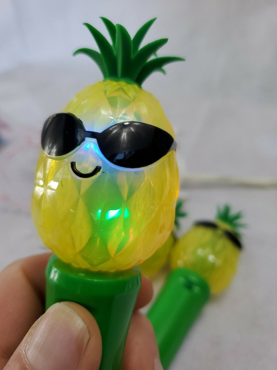 Set of five handheld pineapple-shaped light-up spinner toys, battery operated.