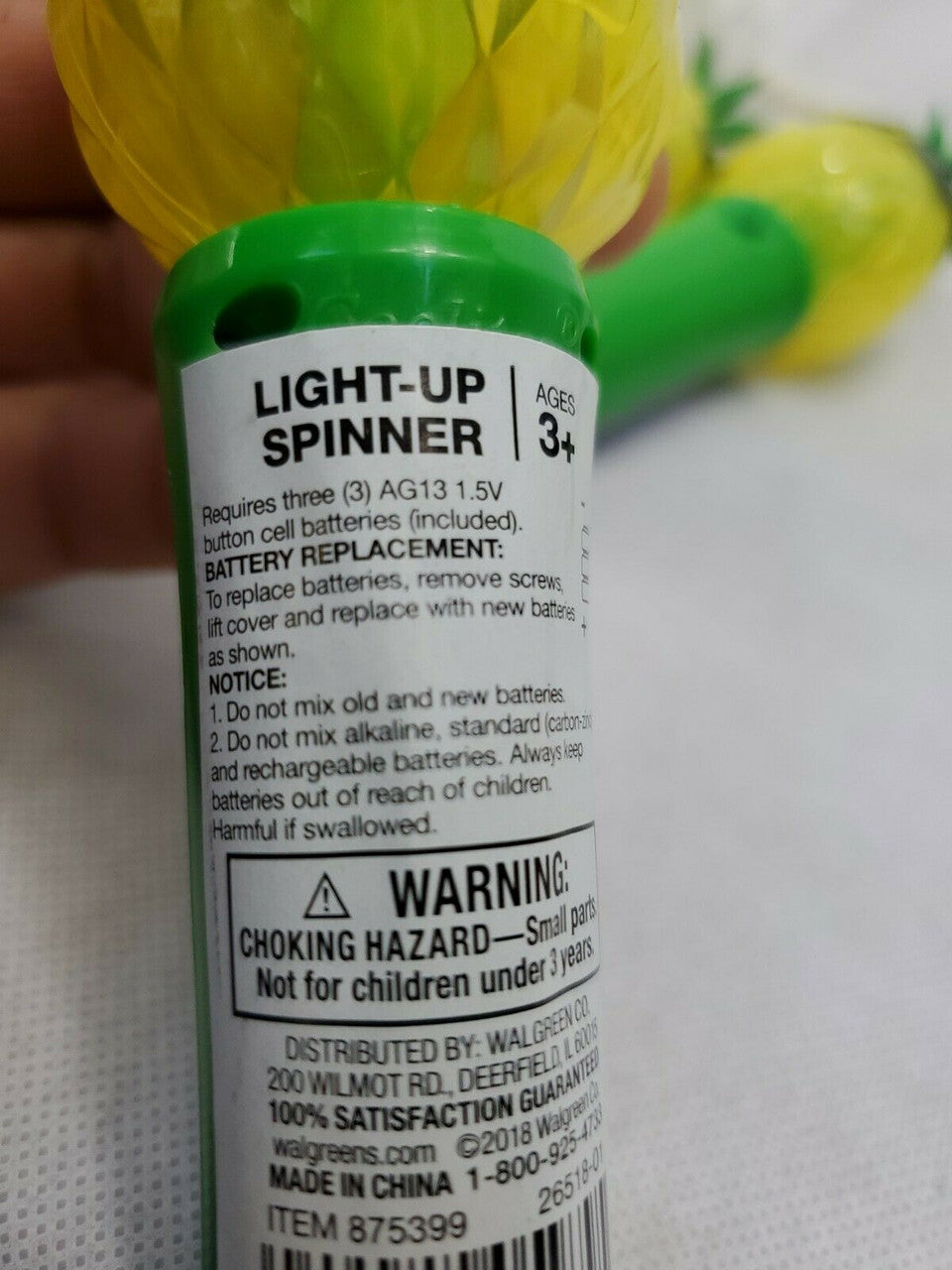 Light-up spinner toy with packaging label showing warning and battery information.