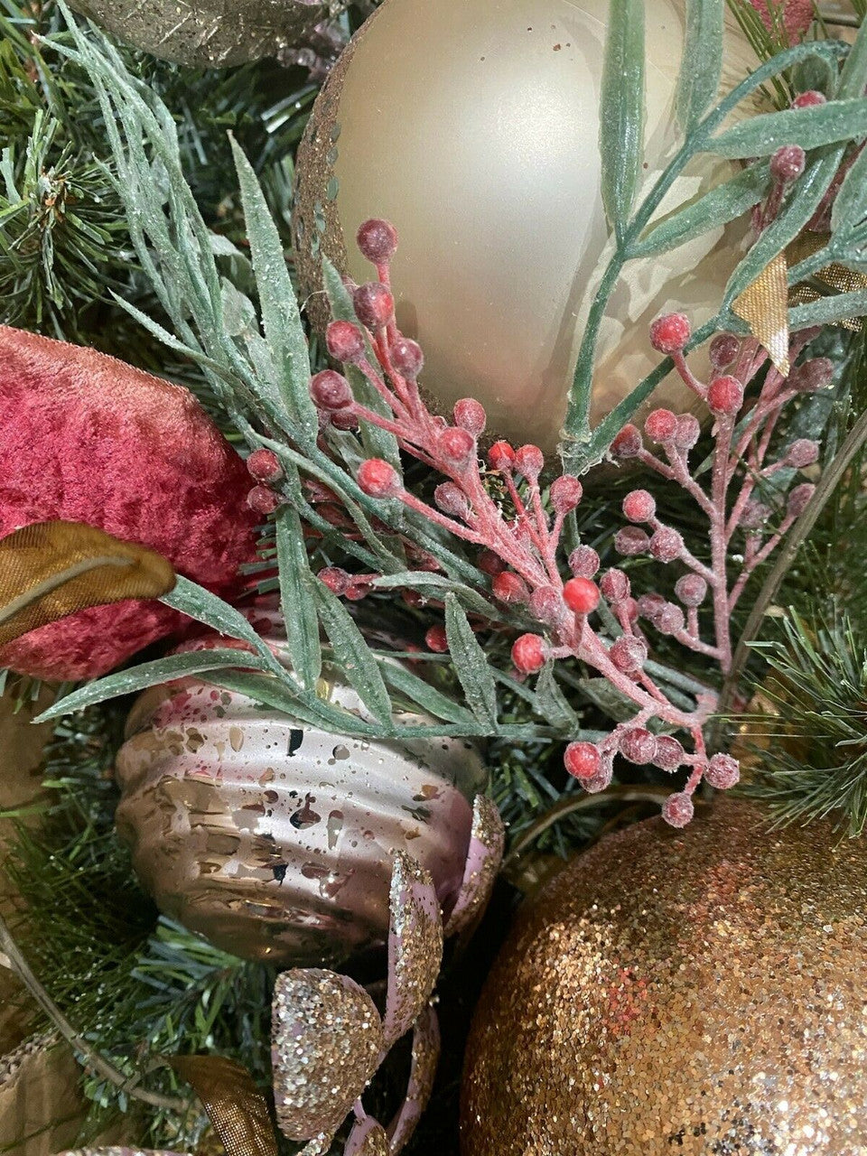 Close-up of decorative Christmas wreath with ornaments and greenery.