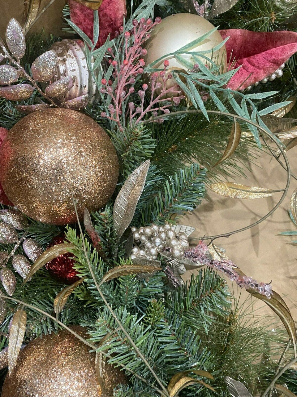 Close-up of a Christmas garland with gold ornaments and greenery.