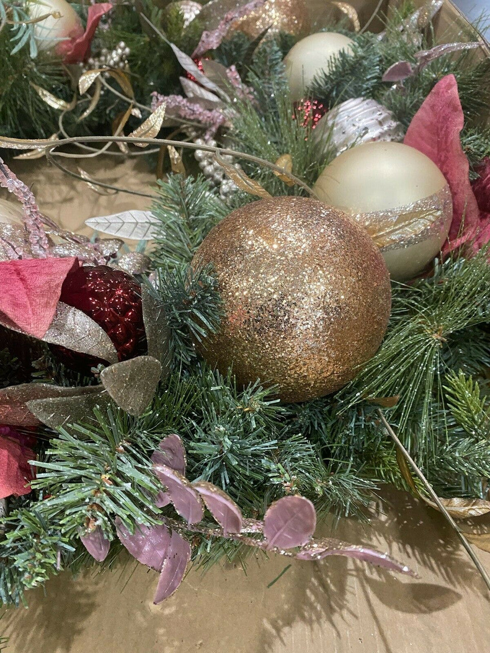 Decorative Christmas wreath with gold ornament and greenery.