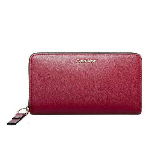 Calvin Klein Red Rock zip-around wristlet wallet with pebble-textured synthetic leather, metal logo on front, and organized interior with multiple card slots and compartments.